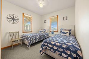1 dormitorio con 2 camas, 1 silla y 2 ventanas en Summer Nights 4 Bedroom Oceanside Home, en Kill Devil Hills