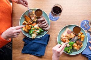 a table with two plates of food and two people holding forks at Parkview Hotel in Orange
