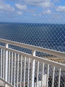 linda vista mar,2 quartos,Ocian SP في برايا جراندي: سياج على شرفة مع المحيط في الخلفية