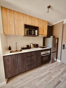 a kitchen with wooden cabinets and a stainless steel refrigerator at Confort de Ñuñoa in Santiago +4 photos