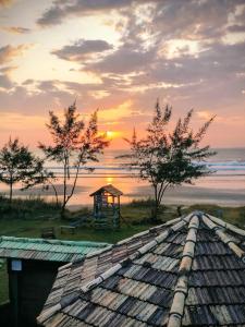 Blick auf einen Pavillon am Strand bei Sonnenuntergang in der Unterkunft Bangalô Pé na Areia in Imbituba
