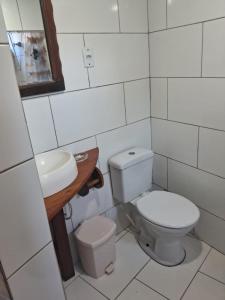 a white bathroom with a toilet and a sink at Bangalô de frente pro mar in Imbituba