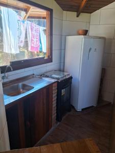 a kitchen with a refrigerator and a sink and a window at Bangalô de frente pro mar in Imbituba