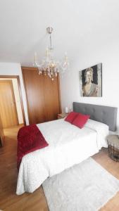 a bedroom with a white bed and a chandelier at Apartamento auditorio centro in Ribeira +2 photos