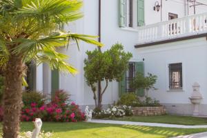 a white building with a palm tree and flowers at Maison Fortune in Castelnuovo del Garda