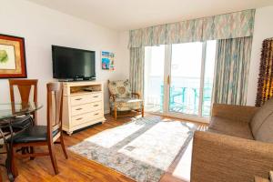 a living room with a tv and a couch and a table at Oceanfront TOP LOCATION MODERN RESORT Lazy River Huge Pool Oasis in Myrtle Beach +37 photos