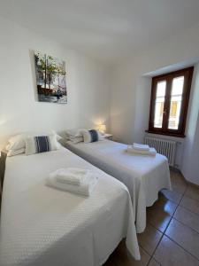 two beds in a room with white walls at Holiday Home by the Beach in Sala Comacina