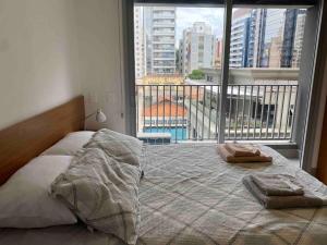uma cama num quarto com uma grande janela em Studio em Pinheiros a uma quadra da Faria Lima em São Paulo