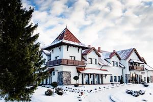 a large white building with a roof in the snow at Hotel Ventus Natural & Medical Spa in Gołdap