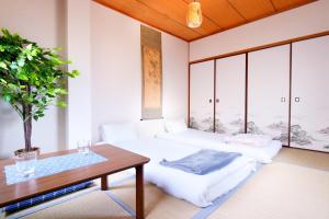 2 Betten in einem Zimmer mit einem Tisch und einer Pflanze in der Unterkunft 和風庵Wafuna 7min walk to Teradacho Loop Line Station in Osaka