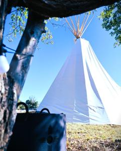 a white tent in a field with a bag at Comanche Teepee at Nomad Landing in Clayton
