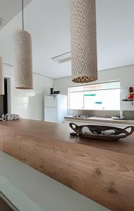 a kitchen with a wooden counter top with lights at Pajuçara Beira Mar e sol in Maceió