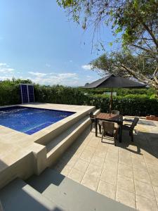 a swimming pool with a table and an umbrella at Casa de campo D&G in Carmen de Apicalá