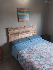 Bett mit einem Kopfteil aus Holz und einem Gemälde an der Wand in der Unterkunft Quinta Don Mario in Riachuelo
