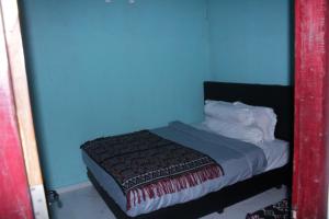 a bedroom with a blue wall and a bed at Novena Bungalow in Pulau Helihana