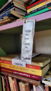 una pila di libri appoggiata su uno scaffale di Casa Rústica Próxima ao Distrito de Milho Verde, 3 QUARTOS - São Gonçalo do Rio das Pedras, Serro a Sêrro