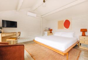 a bedroom with a large white bed and a tv at The Green Room Hotel in Oceanside