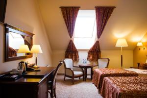 a hotel room with a desk and a bed and a window at Hotel Ventus Natural & Medical Spa in Gołdap