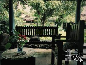 Un banco de madera con una mesa con un jarrón de flores. en Casa Vega, en Izalco