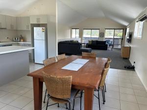 a kitchen and living room with a wooden table and chairs at Trail Stay Mogo in Mogo