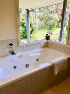 Una bañera grande en un baño con ventana. en Lake Daylesford Villa2 Lake frontage pet friendly, en Daylesford