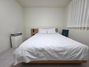 a white bedroom with a large bed with white sheets at Dodam Stay in Seoul