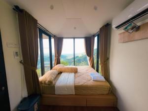 a bedroom with a bed with a large window at Villane Tumpeng Menoreh in Giripurno
