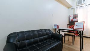 a living room with a couch and a table with a laptop at RedDoorz at David's Travellers Inn Cavite in General Trias