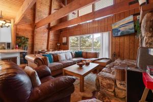 ein Wohnzimmer mit Ledersofas und einem Tisch in der Unterkunft The Cedar Bear Lodge, Jacuzzi with an Outdoor Patio & BBQ in Big Bear City Airport