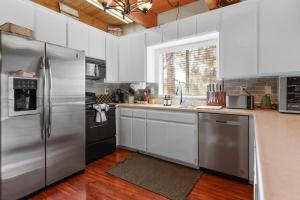 eine Küche mit Küchengeräten aus Edelstahl und weißen Schränken in der Unterkunft The Cedar Bear Lodge, Jacuzzi with an Outdoor Patio & BBQ in Big Bear City Airport