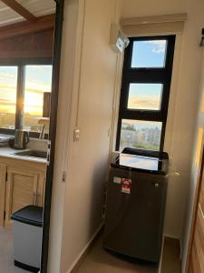 a small refrigerator in a kitchen with a window at Equinox Rooftop Studio in La Gaulette