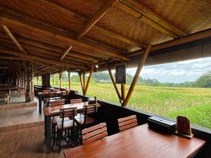 a restaurant with wooden tables and chairs and a field at Besikalung Budget Hostel in Penebel +20 photos