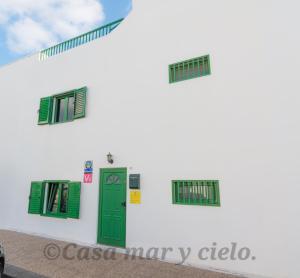 a white building with green windows and a door at Casa mar y cielo in Playa Blanca