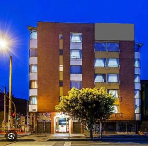 a tall brick building with a tree in front of it at Hostelfc Marly in Bogotá