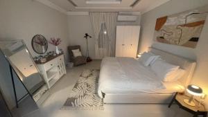 a bedroom with a large white bed and a mirror at Luxury Style Apartment Sari Street in Jeddah
