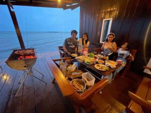 a group of people sitting around a table with food at ชานไม้ ใน เล เกาะช้าง in Ban Dan Kao