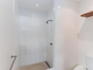 a bathroom with a shower with white tiles at Luxury Oceanfront Haven with a Private Rooftop Spa in Kingscliff +30 photos