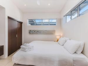 a white bedroom with a large bed and windows at Luxury Oceanfront Haven with a Private Rooftop Spa in Kingscliff
