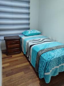 a bed with a blue comforter and a night stand at Céntrico y confortable, 2 camas in La Paz