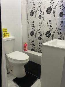 a bathroom with a toilet and a shower curtain at White Room Sparks in Spanish Town +12 photos