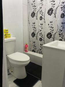 a bathroom with a toilet and a shower curtain at White Room Sparks in Spanish Town