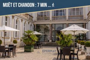 a patio with tables and umbrellas in front of a building at Magnum 80 Terrasse & Climatisation - 6 personnes - BnB Epernay in Épernay