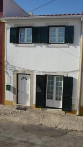una casa blanca con persianas negras y una puerta en Casa de Férias Azeitão, en Azeitão