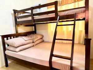 a bunk bed with a ladder and pillows on it at Your Comfort Zone Staycation1 in Manila