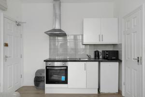 a kitchen with white cabinets and a stove top oven at Startlet Stays Apartments - On Elizabeth Line with Free Parking in London