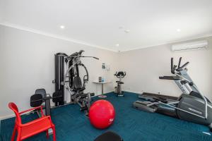 - une salle de sport avec deux vélos d'exercice et une chaise rouge dans l'établissement Escape to Villa 4 - Cape View Resort, à Broadwater