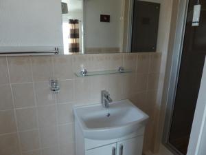 a bathroom with a sink and a mirror at The Denewood in Sandown