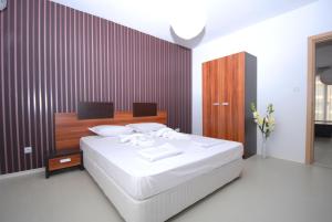 um quarto com uma cama branca e uma parede de madeira em Boutique Suites Rainbow 4 em Sunny Beach