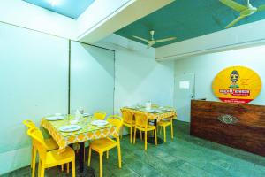 a dining room with two tables and yellow chairs at Treebo Elmas Grand in Bengaluru