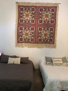 Una habitación con dos camas y una alfombra colgada en la pared. en Casa Historica Colonial, en Álamos